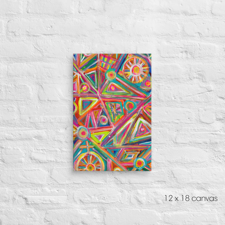 The Tropical Geometry Canvas Artwork by My Favourite Colour is Rainbow features vibrant geometric patterns of triangles, circles, and lines in lively colors on a 12x18 canvas, beautifully displayed against a white brick wall.