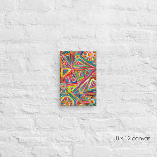 The Tropical Geometry Canvas Artwork by My Favourite Colour is Rainbow is a vibrant abstract piece showcasing triangles and circles in pink, blue, and yellow. Displayed on a white brick wall, this artwork measures 8 x 12 inches with dimensions noted in the bottom right corner.