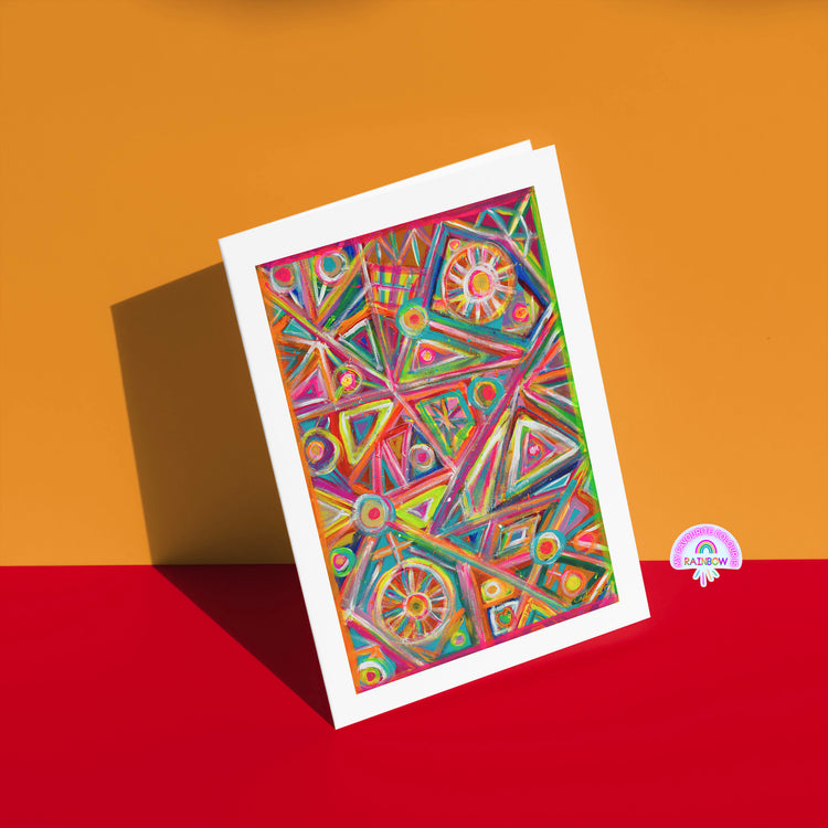 The Tropical Geometry Greeting Card by My Store displays bold triangles, circles, and lines on a vivid orange and red background with a small RAINBOW logo in the bottom right corner.