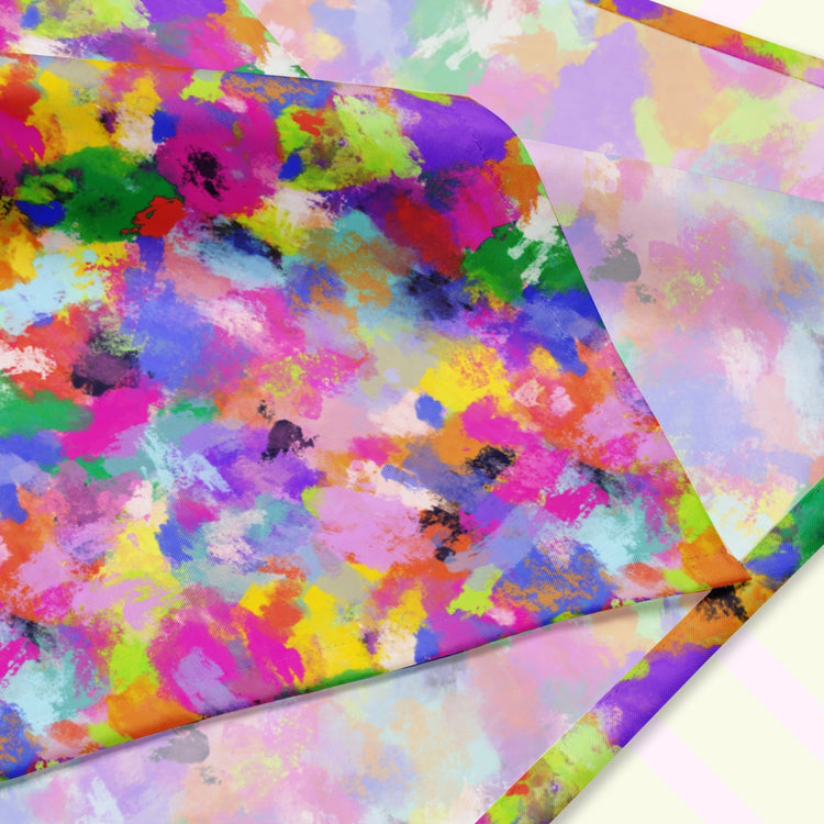 A closeup of the 'Watercolour Rainbow' Bandana by My Favourite Colour is Rainbow featuring a vibrant abstract design with blue, green, pink, orange, and purple splashes. The design is printed on only one side of the bandana.