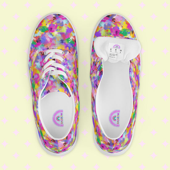 A top view of colorful Watercolour Rainbow Canvas Sneakers by My Favourite Colour is Rainbow on a pastel, patterned background reveals splashes of pink, purple, blue, yellow, and green with one shoes inner label and size.