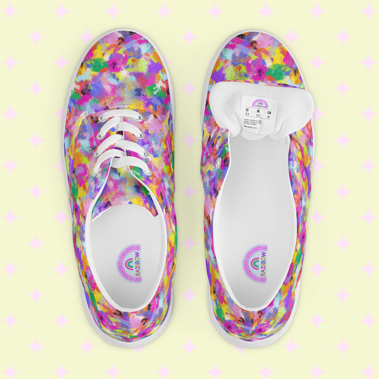 A top view of colorful Watercolour Rainbow Canvas Sneakers by My Favourite Colour is Rainbow on a pastel, patterned background reveals splashes of pink, purple, blue, yellow, and green with one shoes inner label and size.