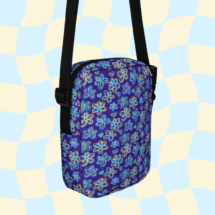 The Bloomscape Mini Crossbody Bag by My Favourite Colour is Rainbow features a vibrant floral-inspired print on a blue background, complemented by a black strap. Its light blue and cream wavy checkered pattern adds style while being water-resistant.