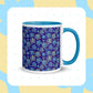 The My Favourite Colour is Rainbow Bloomscape Mug is a white ceramic mug with a blue interior and handle, featuring blue and yellow flowers on a dark blue background, complemented by soft blue and beige patterns—perfect for your morning coffee ritual.