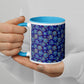 A person cradles a Bloomscape Mug by My Favourite Colour is Rainbow, featuring a white and yellow floral design on deep blue. The light blue interior and handle accentuate polished nails for an elegant coffee ritual moment.