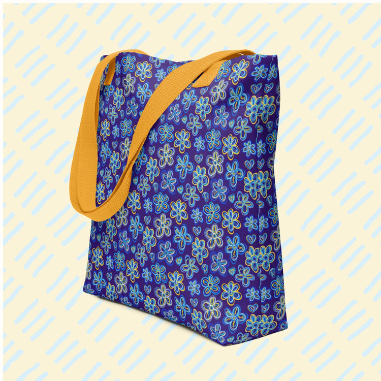 The Bloomscape Tote Bag by My Favourite Colour is Rainbow features floral and heart patterns in yellow and blue on a blue base.  It has a yellow handles.