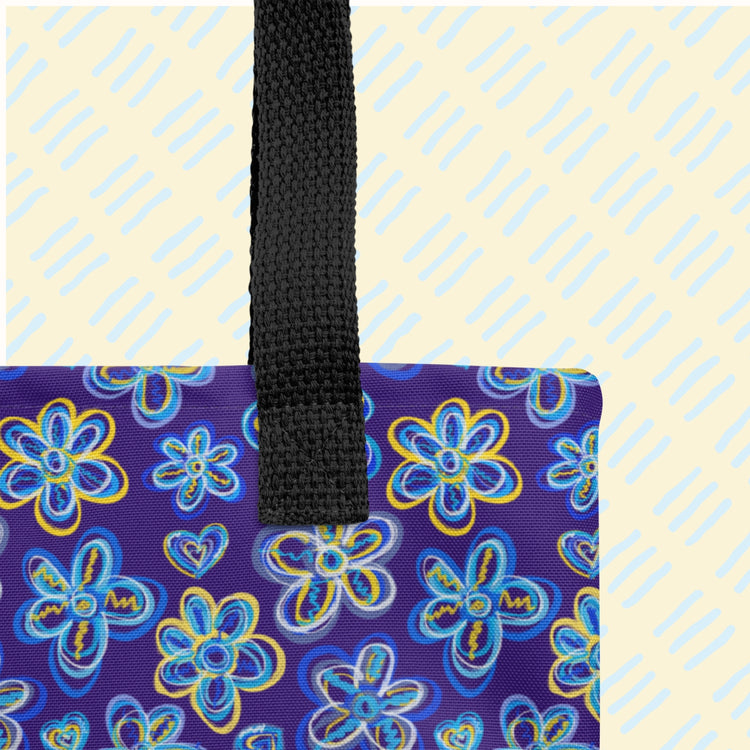 The Bloomscape Tote Bag by My Favourite Colour is Rainbow is a spacious tote bag featuring a vibrant flower pattern on a dark blue background, with black handles. 