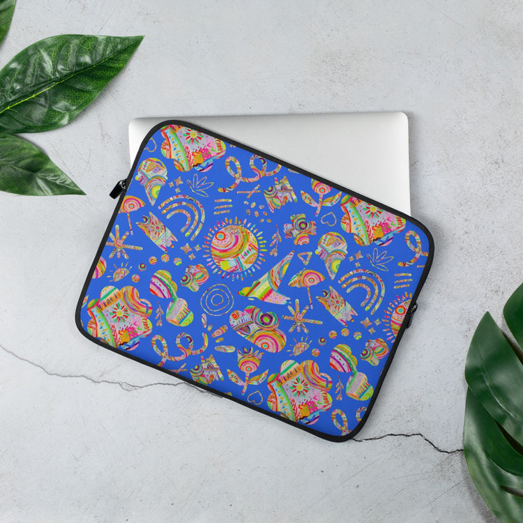 The 13" Blue Summer Sorbet Laptop Sleeve by My Favourite Colour is Rainbow, featuring  cut outs of my Summer Sorbet print in a fun mix of suns, rainbows, ice creams and other abstract shapes, set against a striking blue backdrop. A silver laptop is partially out of the laptop sleeve, resting on a light gray surface with green leaves nearby.  The print is on only one side of the laptop sleeve, the other side is black.