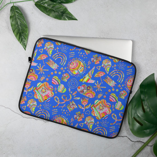 The 13" Blue Summer Sorbet Laptop Sleeve by My Favourite Colour is Rainbow, featuring  cut outs of my Summer Sorbet print in a fun mix of suns, rainbows, ice creams and other abstract shapes, set against a striking blue backdrop. A silver laptop is partially out of the laptop sleeve, resting on a light gray surface with green leaves nearby.  The print is on only one side of the laptop sleeve, the other side is black.