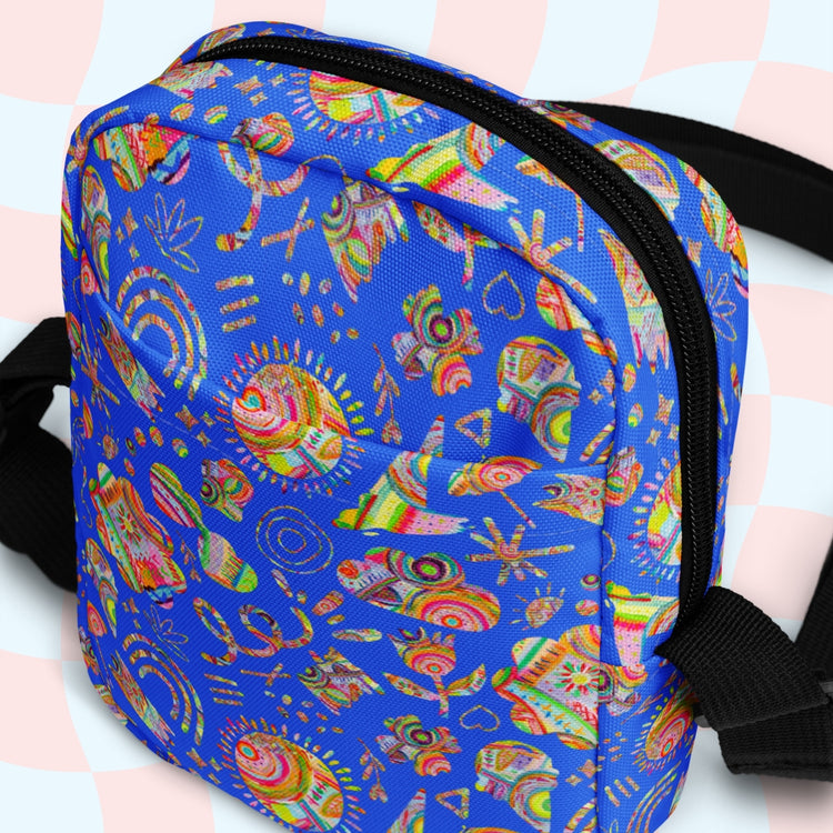 The Blue Summer Sorbet Mini Crossbody Bag by My Favourite Colour is Rainbow features vibrant abstract tribal-style patterns with symbols. Its water-resistant, has adjustable black straps and a visible zipper, all set on a soft checkered light pink and blue background.