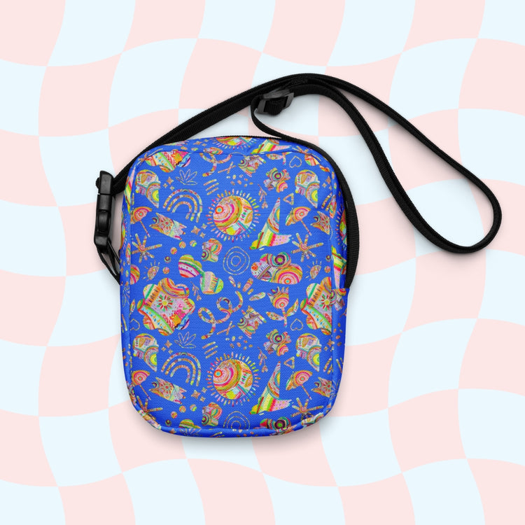 The Blue Summer Sorbet Mini Crossbody Bag by My Favourite Colour is Rainbow features a colorful abstract pattern with swirls, triangles, and shapes on a blue backdrop. This water-resistant bag has sturdy construction and an adjustable black strap against a pastel checkered design.