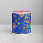 Introducing the Blue Summer Sorbet Mug by My Favourite Colour is Rainbow: a ceramic wonder with a bright pink interior, vibrant blue exterior, and adorned with multicolored patterns and floral designs on a light gray surface.