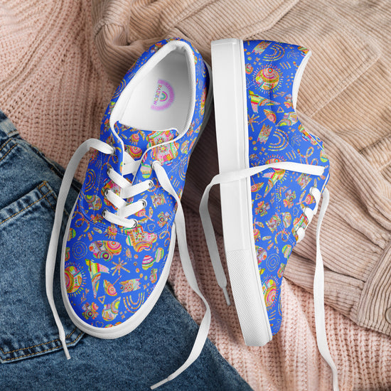 A pair of Blue Summer Sorbet Canvas Sneakers by My Favourite Colour is Rainbow, featuring colourful geometric patterns and white laces, sits on a flat lay of a pink sweater and denim jeans.