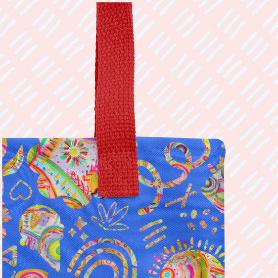 A close-up of the Blue Summer Sorbet Tote Bag from My Favourite Colour is Rainbow, featuring a sturdy red handle and a spacious design with vibrant blue fabric, adorned with abstract patterns in red, yellow, green, and orange. 