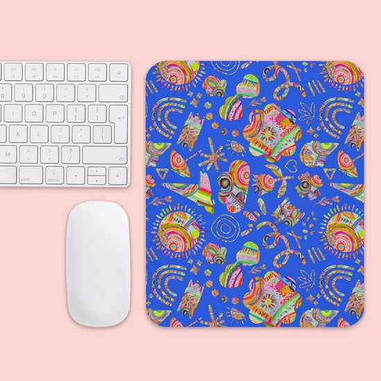 A computer keyboard and mouse sit beside the Blue Summer Sorbet Mouse Pad by My Favourite Colour is Rainbow, featuring colorful abstract designs set against a pink background.