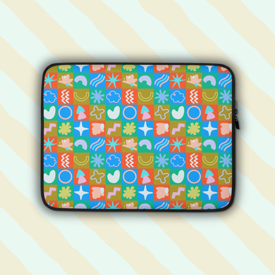 The Colour Block Laptop Sleeve by My Favourite Colour is Rainbow features vibrant abstract shapes like circles, stars, waves, and flowers in colours with a vintage vibe.  It is set against a pastel background.  The print is on only one side of the laptop sleeve, the other side is black.
