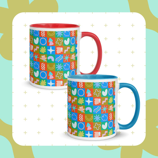 Two vibrant Colour Block Mugs by My Favourite Colour is Rainbow exhibit multicolored geometric and abstract designs. One has a red handle and interior, while the other boasts blue. The background features a light green leafy pattern dotted with small plus signs.