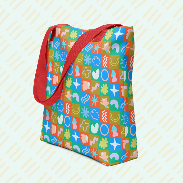 My Favourite Colour is Rainbows Colour Block Tote Bag features a trendy design with a spacious interior and sturdy red handles. It showcases a playful pattern of multicoloured squares, each filled with abstract shapes like flowers, stars, and squiggles.