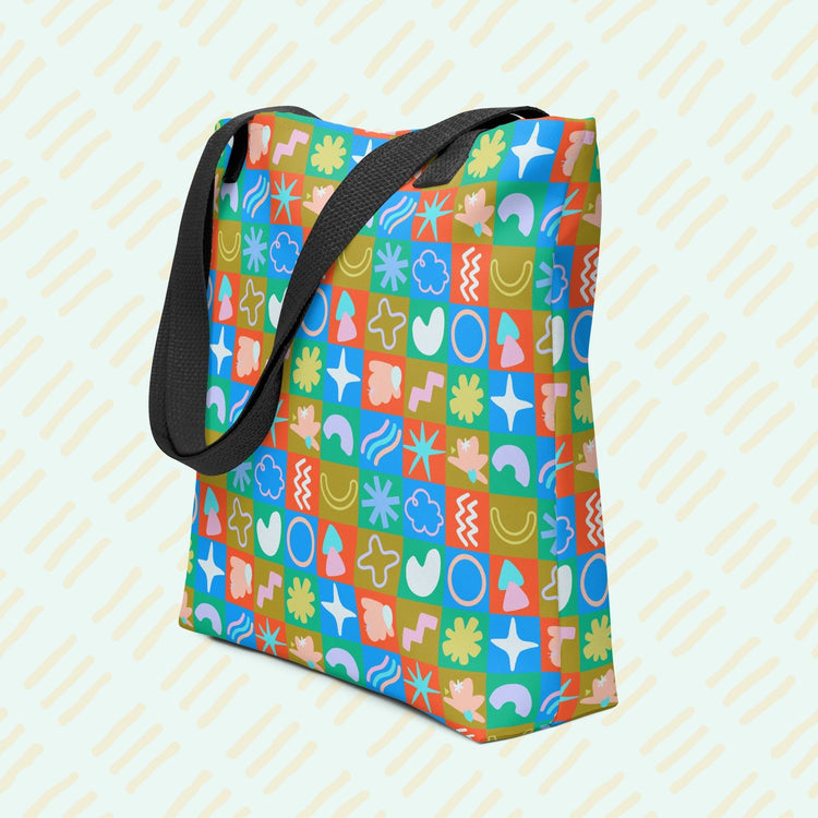 My Favourite Colour is Rainbows Colour Block Tote Bag features a trendy design with a spacious interior and sturdy black handles. It showcases a playful pattern of multicoloured squares, each filled with abstract shapes like flowers, stars, and squiggles.