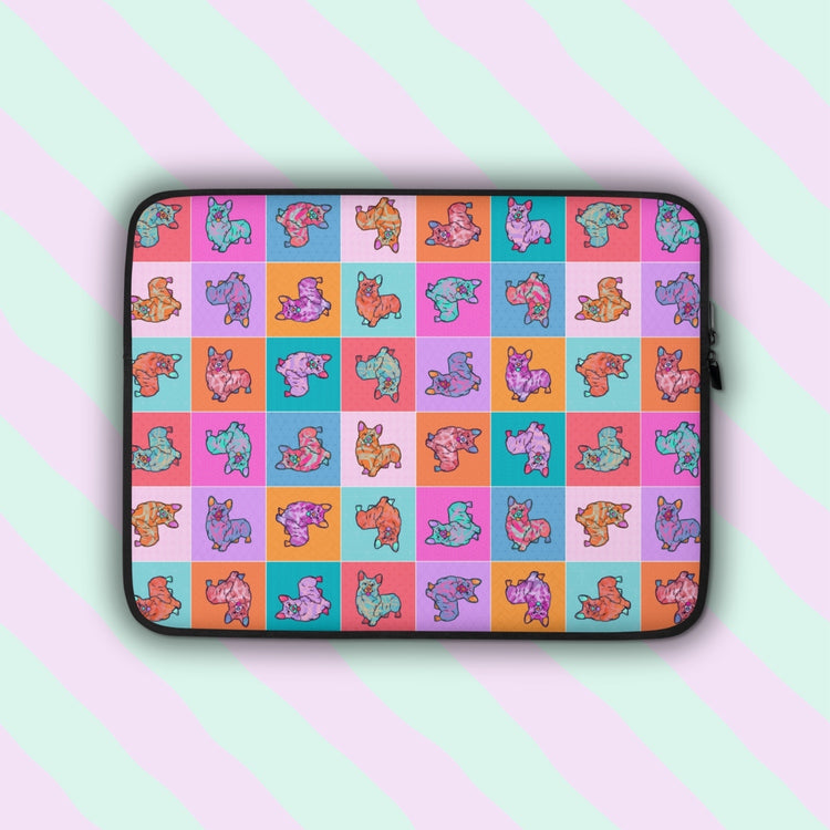 The Crazi Corgis Laptop Sleeve by My Favourite Colour is Rainbow features a vibrant pop art-style design of illustrated corgis on a checkered background in shades of pink, red, orange, blue and teal.