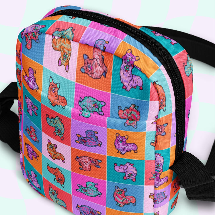 The Crazi Corgis Mini Crossbody Bag by My Favourite Colour is Rainbow showcases cartoon corgis in playful poses on a grid of pink, orange, and blue squares. This colorful, water-resistant bag boasts adjustable straps for comfort.