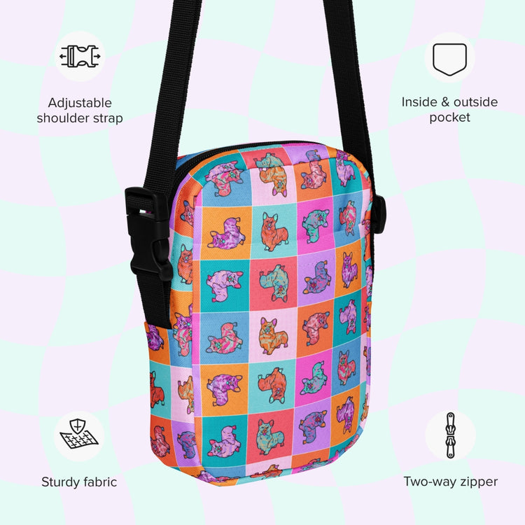 The Crazi Corgis Mini Crossbody Bag by My Favourite Colour is Rainbow showcases a cartoon animal grid pattern against a light checkered background. Its sturdy and water-resistant, featuring a black adjustable strap, durable fabric, two-way zipper, and both inside and outside pockets.