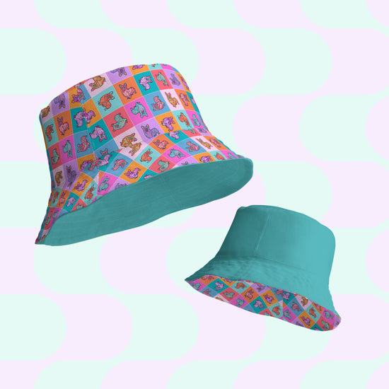 Set against a pastel polka dot backdrop, the Crazi Corgis Reversible Bucket Hat by My Favourite Colour is Rainbow blends style and versatility with one side featuring a cartoon character pattern and the other mainly teal with a patterned brim, crafted from breathable fabric for comfort.