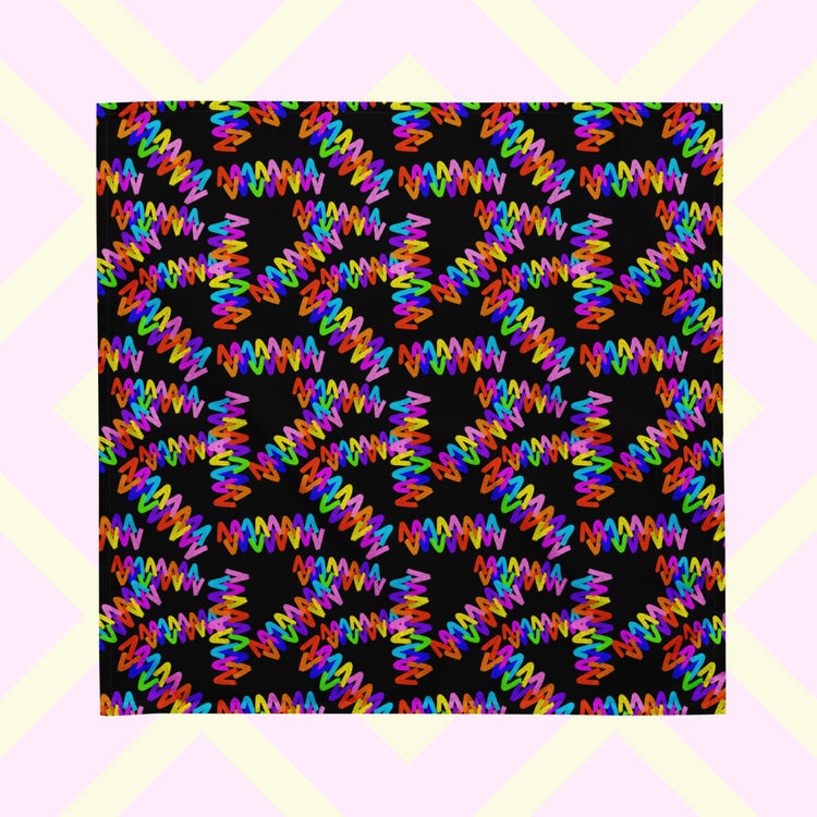 The Electric Zigzag Bandana by My Favourite Colour is Rainbow displays a striking abstract pattern of colourful zigzag lines in red, blue, purple, and green on a black square background.