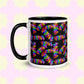 The Electric Zigzag Mug by My Favourite Colour is Rainbow is a ceramic mug with a black handle and rim, featuring a vibrant zigzag pattern in red, blue, green, and yellow over a black background. Its light yellow backdrop displays a subtle pink quatrefoil design—ideal for brightening your coffee break.