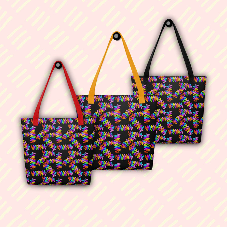 Three Electric Zigzag Tote Bags by My Favourite Colour is Rainbow, with red, yellow and black handles, hang on hooks.  The bag features a vibrant zigzag pattern in bright rainbow colours: red, orange, yellow, green, blue, purple and pink.