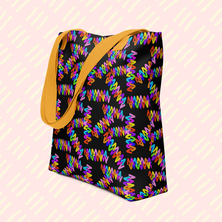 The Electric Zigzag Tote Bag by My Favourite Colour is Rainbow featuring a vibrant zigzag pattern in bright rainbow colours: red, orange, yellow, green, blue, purple and pink.  This version has a yellow handle.