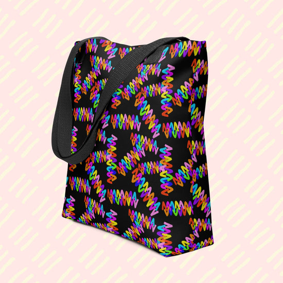 The Electric Zigzag Tote Bag by My Favourite Colour is Rainbow featuring a vibrant zigzag pattern in bright rainbow colours: red, orange, yellow, green, blue, purple and pink.  This version has a black handle.