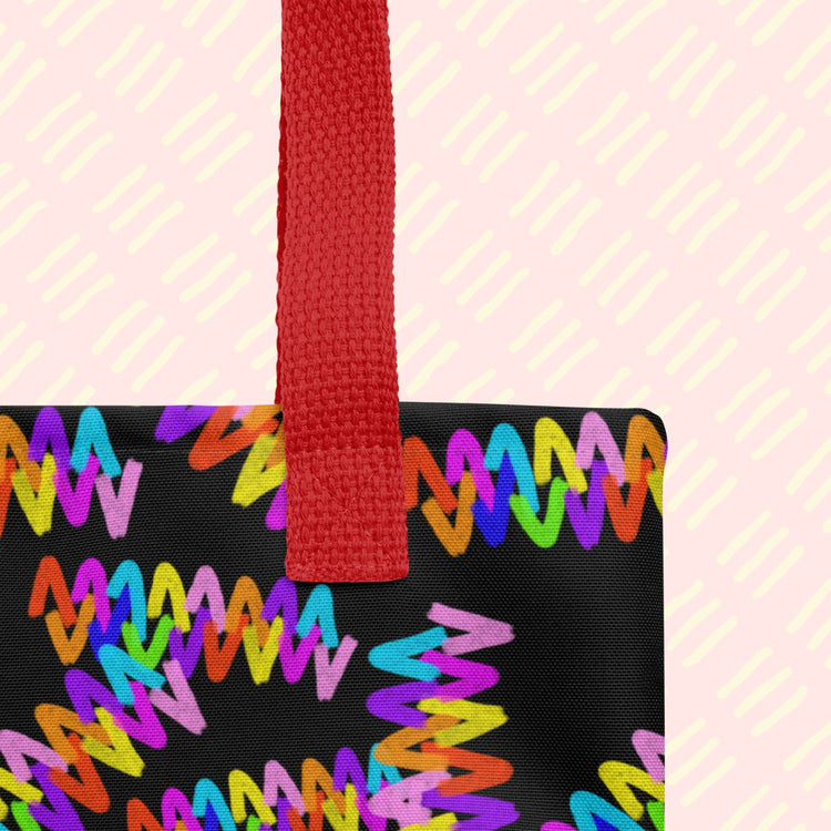 Close-up of the Electric Zigzag Tote Bag by My Favourite Colour is Rainbow, showing the sturdy black handle. 
 The bag has  a vibrant rainbow zigzag design on black.