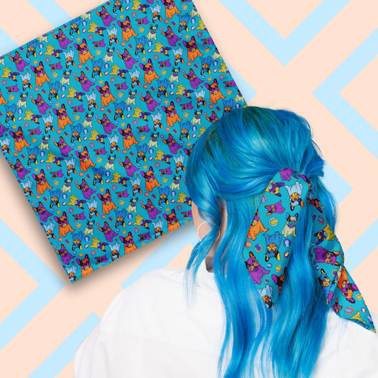 Two views of the 'Frenchie Fetch, Set, Match' Bandana by My Favourite Colour is Rainbow.  At top left, a flat lay of the bandana.  At bottom right, a person with vibrant blue hair is seen from behind, wearing the bandana in her hair.  The Frenchie Fetch, Set, Match Bandana showcases purple, orange, yellow and blue french bulldogs and tennis balls on a blue backdrop. 
