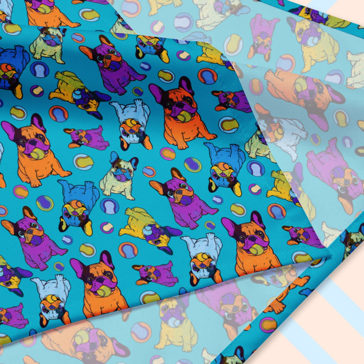 A closeup of the 'Frenchie Fetch, Set, Match' Bandana by My Favourite Colour is Rainbow featuring purple, orange, yellow and blue french bulldogs and tennis balls on a blue backdrop.  The design is printed on only one side of the bandana.