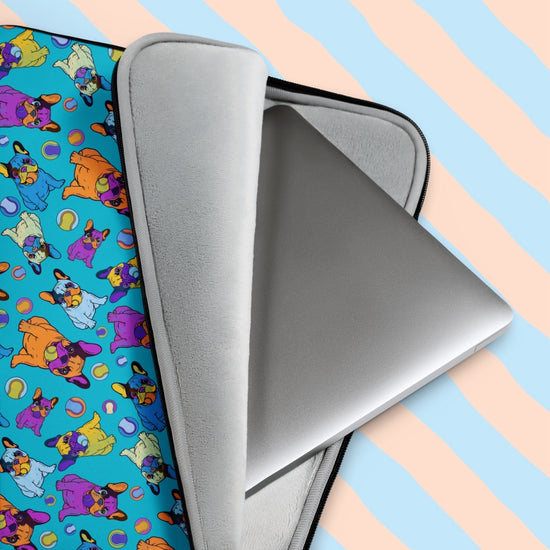 A silver laptop peeks out of My Favourite Colour is Rainbows vibrant Frenchie Fetch, Set, Match Laptop Sleeve, adorned with cartoonish french bulldogs and tennis balls.  The print is on only one side of the laptop sleeve, the other side is black.