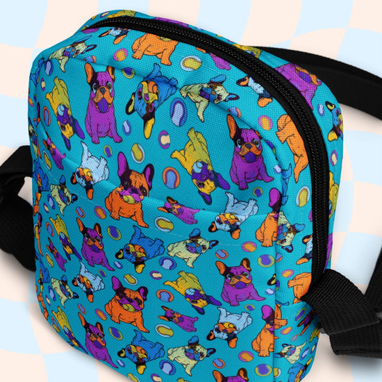 The Frenchie Fetch, Set, Match Mini Crossbody bag by My Favourite Colour is Rainbow highlights cartoon French Bulldogs on a turquoise backdrop with pastel checkered patterns. It features adjustable black shoulder straps and offers a colorful, water-resistant design for whimsical charm.