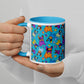 A person with neatly manicured nails holds a My Favourite Colour is Rainbow Frenchie Fetch, Set, Match Mug. Its a white coffee mug with a blue interior and features colorful bulldogs with playful orange, purple, and blue elements on the bright backdrop.