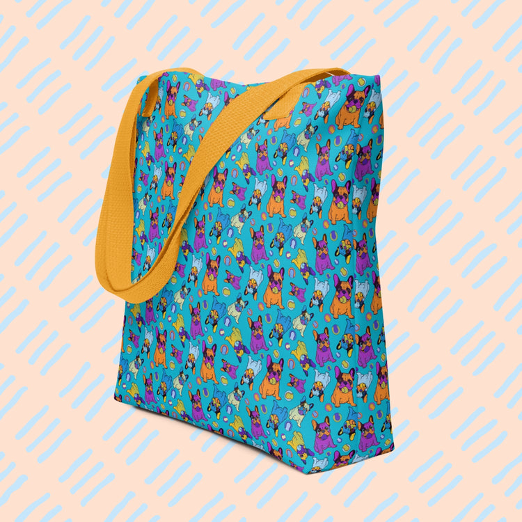 The Frenchie Fetch, Set, Match Tote Bag by My Favourite Colour is Rainbow  features colourful cartoon french bulldog and tennis ball designs on a bright blue background. It has a sturdy yellow strap.