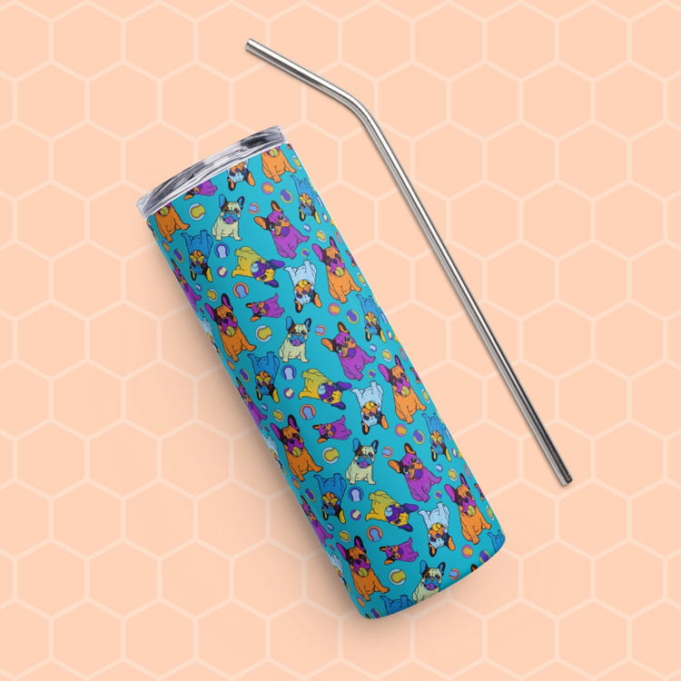 The Frenchie Fetch, Set, Match Stainless Steel Tumbler by My Favourite Colour is Rainbow, featuring a vibrant cartoon cat design in blue, rests beside a metal straw on a beige honeycomb-patterned background.