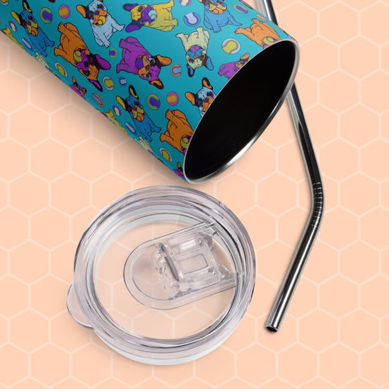 The Frenchie Fetch, Set, Match Stainless Steel Tumbler by My Favourite Colour is Rainbow rests on a hexagonal surface. Featuring playful dog patterns in bright colors, it comes with a clear plastic cup lid and a metal straw.