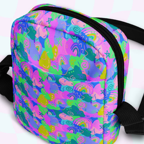 The Funfetti Mini Crossbody Bag by My Favourite Colour is Rainbow features a vibrant unicorn and rainbow pattern in neon pink, blue, green, and yellow. With black straps and zippers, it captures a playful Funfetti vibe while offering hands-free convenience for any adventure.