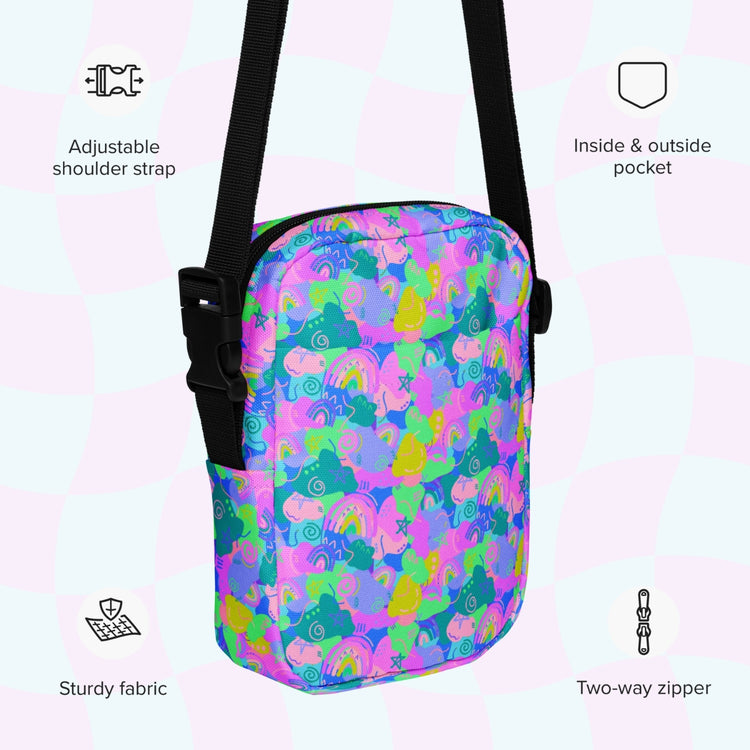 The Funfetti Mini Crossbody Bag by My Favourite Colour is Rainbow features a lively design with rainbows, unicorns, and stars on a pastel checkered background. It has an adjustable strap, inside and outside pockets, durable fabric, and a two-way zipper for hands-free convenience.