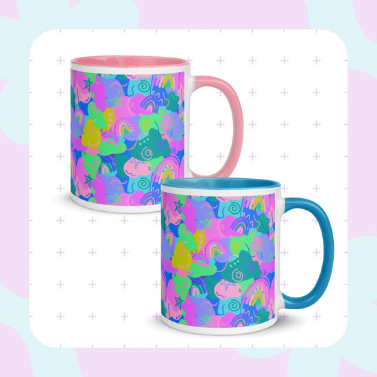 The My Favourite Colour is Rainbow brands Funfetti Mugs come in a set of two, featuring colorful ceramic with pink and blue handles. They display a vibrant abstract unicorn and rainbow pattern on a light background with a subtle cross design for added whimsy.