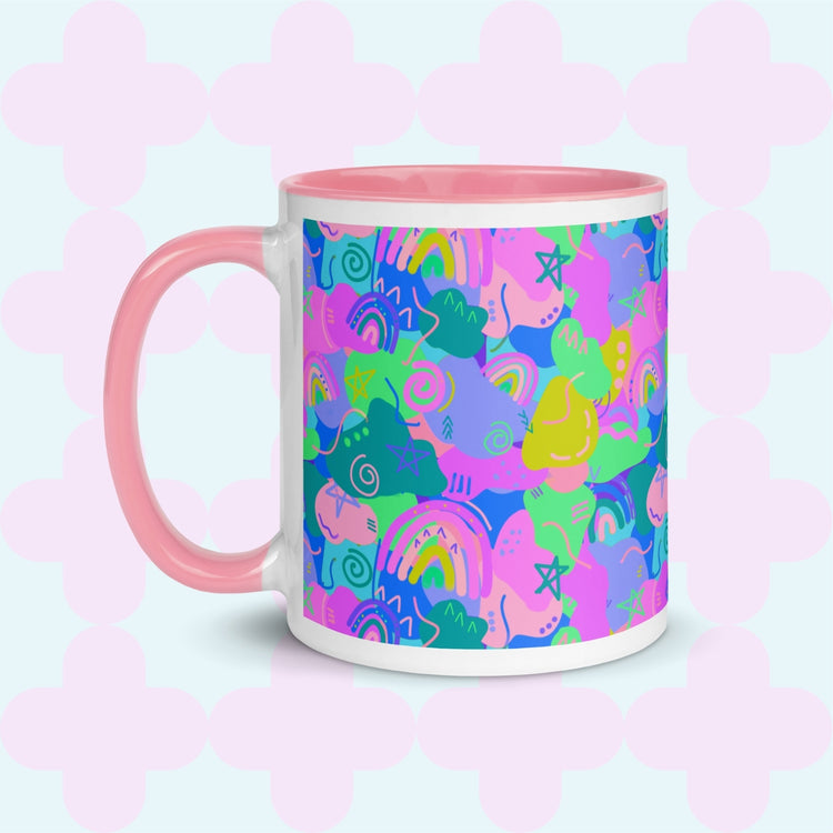 The Funfetti Mug from My Favourite Colour is Rainbow is a ceramic, abstract-patterned delight featuring a pink handle and rim, with doodles in blue, green, pink, and purple on a light background with a subtle cross pattern.