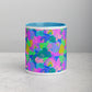 The Funfetti Mug by My Favourite Colour is Rainbow features a vibrant ceramic design with an abstract pattern in blue, pink, green, and purple. Shapes resemble rainbows, spirals, and stars. The interior is light blue and it rests on a light gray surface.
.