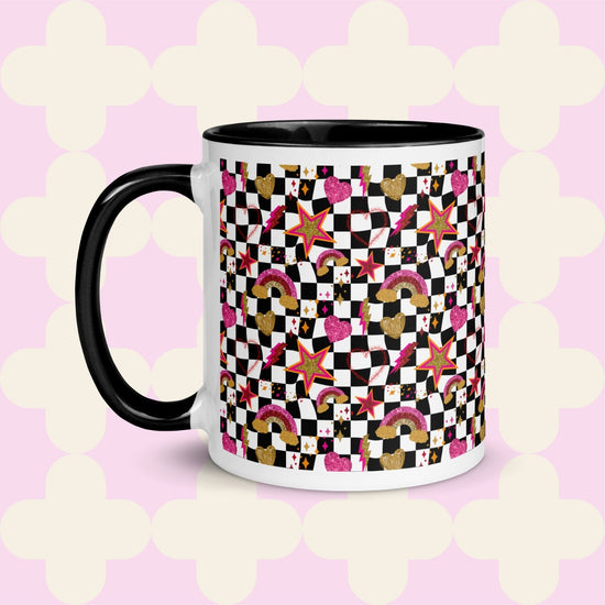 The Galaxy Mug by My Favourite Colour is Rainbow is a ceramic masterpiece featuring a black handle and rim, vibrant stars, hearts, rainbows, and squares on a light pink backdrop with white quatrefoil patterns.