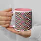 A person with neutral-toned nails holds the My Favourite Colour is Rainbows Galaxy Mug, a white ceramic piece with a pink interior adorned with colorful geometric patterns, rainbows, stars, hearts, and checkerboard designs.