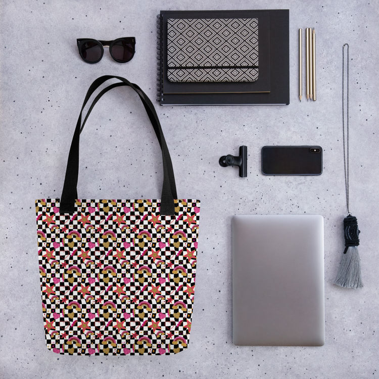 A flat lay features a Galaxy Tote Bag by My Favourite Colour is Rainbow with black sunglasses, a patterned notebook, two pens, a chic black clip, smartphone, silver laptop, and decorative tassel keychain on a grey surface.