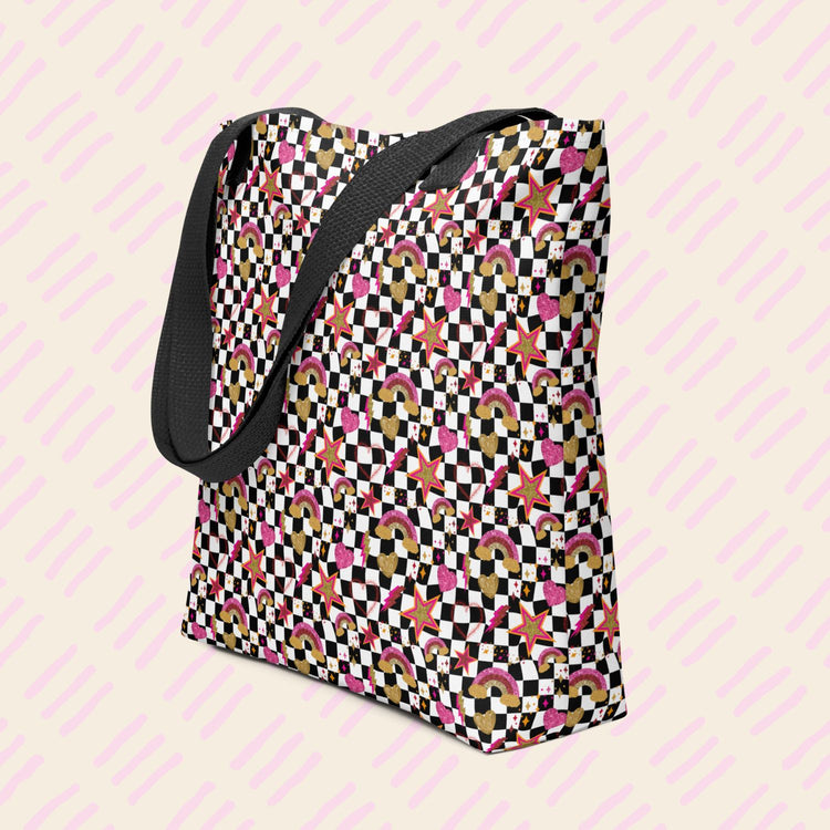 The Galaxy Tote Bag by My Favourite Colour is Rainbow is a spacious tote featuring a black strap and decorated with a black-and-white checkerboard pattern with stars, rainbows and hearts in glittery gold, pink and red.